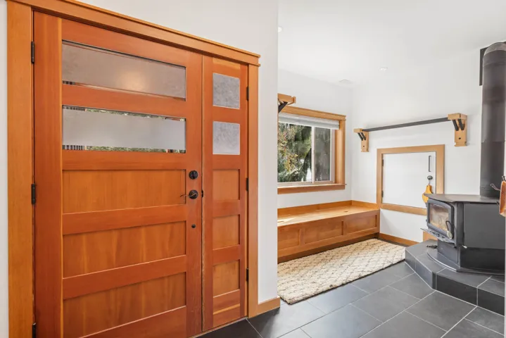 Foyer with dark tile patterned flooring, a wood stove, and baseboards
