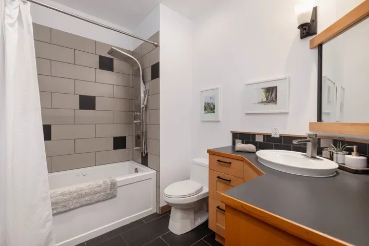 Bathroom with tile patterned flooring, shower / tub combo with curtain, vanity, and toilet