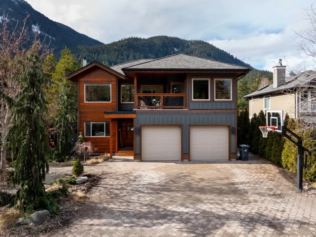 Chalet / cabin featuring an attached garage, a balcony, a mountain view, a shingled roof, and driveway