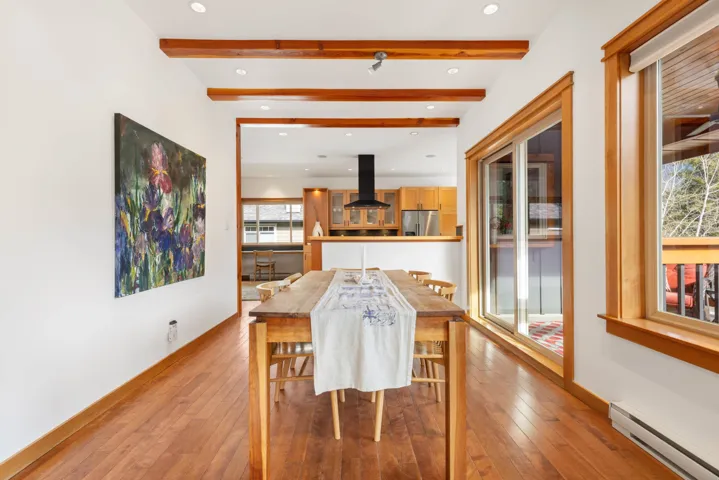 Dining area featuring a baseboard heating unit, light wood-type flooring, beamed ceiling, and baseboards