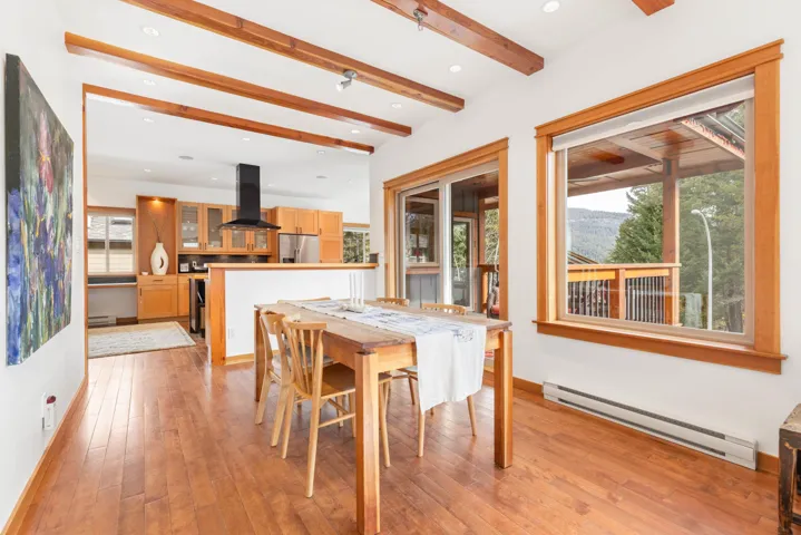 Dining room featuring a wealth of natural light, a baseboard radiator, light wood-style floors, and beamed ceiling