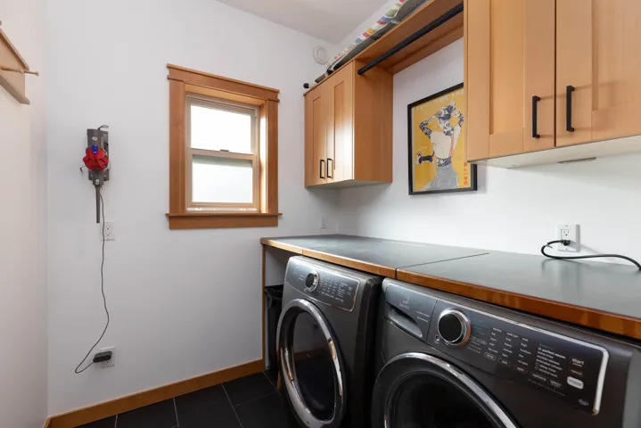 Washroom featuring cabinet space, baseboards, dark tile patterned flooring, and independent washer and dryer