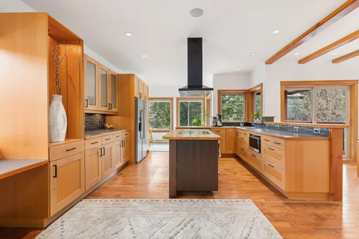 Kitchen with a center island, stainless steel appliances, light wood-style flooring, glass insert cabinets, and island range hood