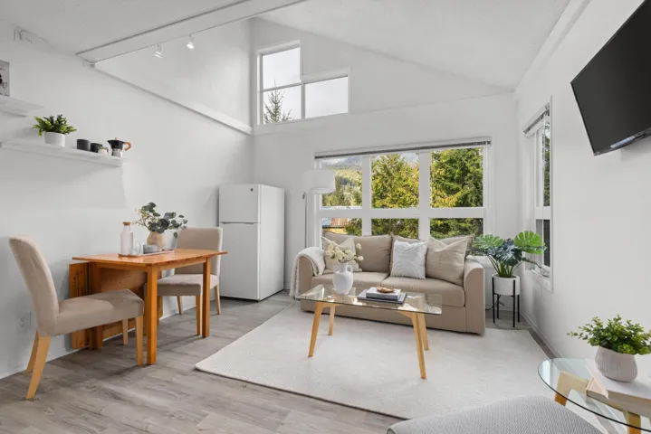 Living room with light wood-type flooring, healthy amount of natural light, a high textured ceiling, and track lighting