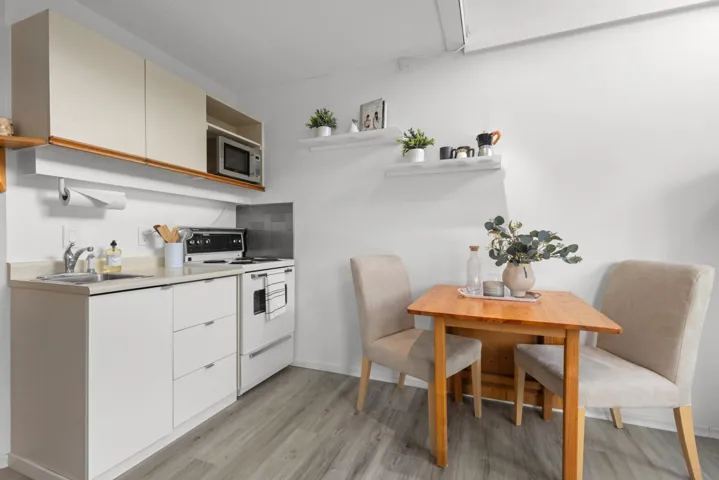 Kitchen with open shelves, light countertops, electric range, stainless steel microwave, and light wood finished floors