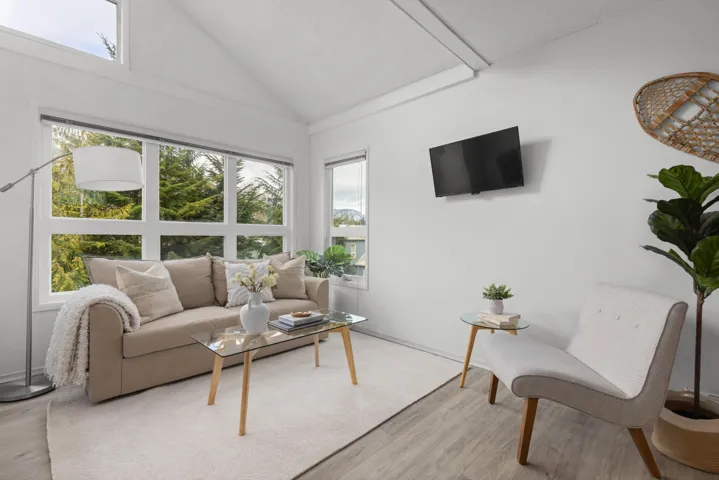 Living room with lofted ceiling, healthy amount of natural light, and light wood-style flooring