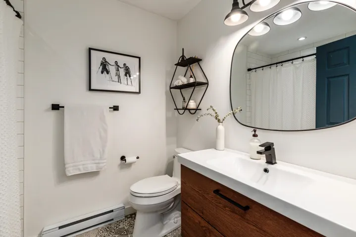 Bathroom featuring a baseboard heating unit, curtained shower, toilet, and vanity