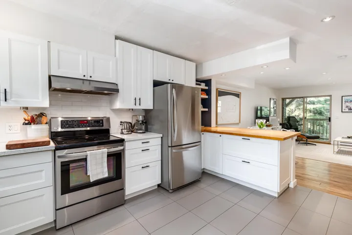 Kitchen with white cabinetry, stainless steel appliances, under cabinet range hood, open floor plan, and a peninsula