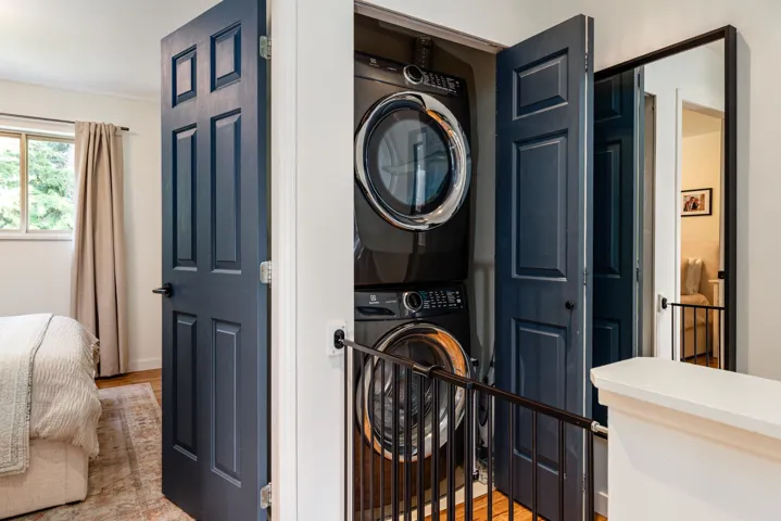 Laundry room featuring wood finished floors, stacked washing maching and dryer, and laundry area