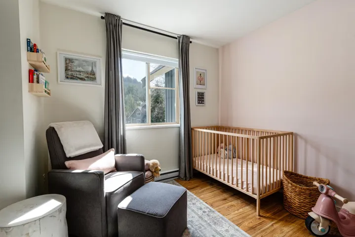 Bedroom with a crib, wood finished floors, and a baseboard radiator
