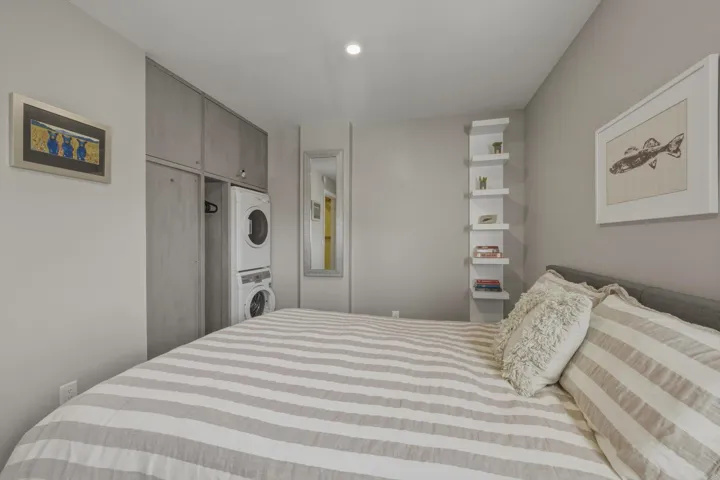 Integrated laundry appliances within custom cabinetry, recessed lighting, and built-in corner shelving