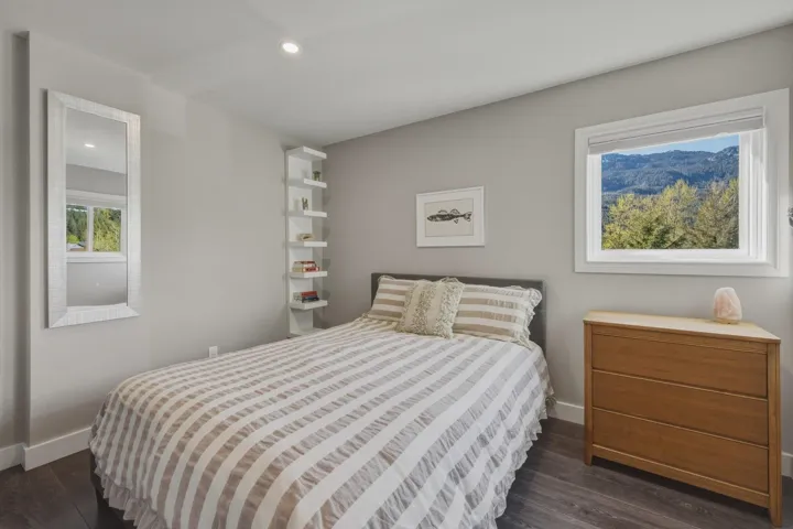 Bedroom featuring a window with mountain and tree scenery, recessed ceiling lighting, dark wood-finish flooring, and a built-in vertical shelving unit