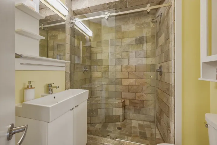 Walk-in shower featuring natural stone-look tiling and a built-in bench