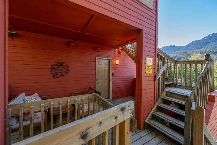 Covered exterior patio featuring wood-finish siding, a private entry door, and a built-in wooden staircase