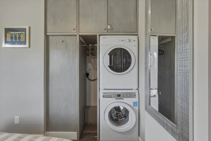 Dedicated laundry area featuring a stacked washer and dryer unit, integrated into custom cabinetry