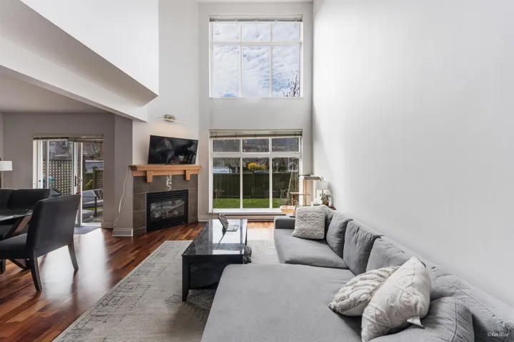 Living room featuring a healthy amount of sunlight, wood finished floors, a towering ceiling, and a tile fireplace