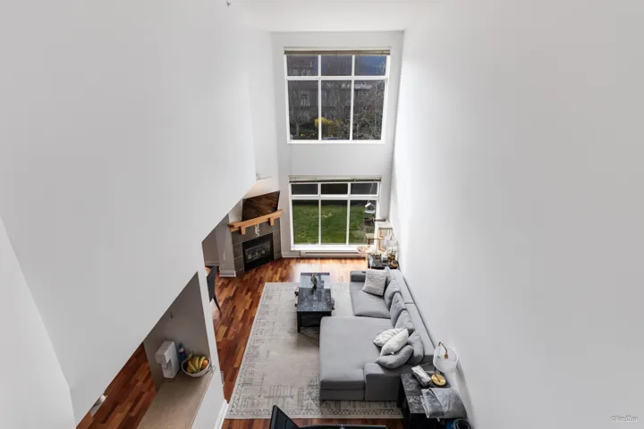 Living room with a towering ceiling, wood finished floors, and a fireplace
