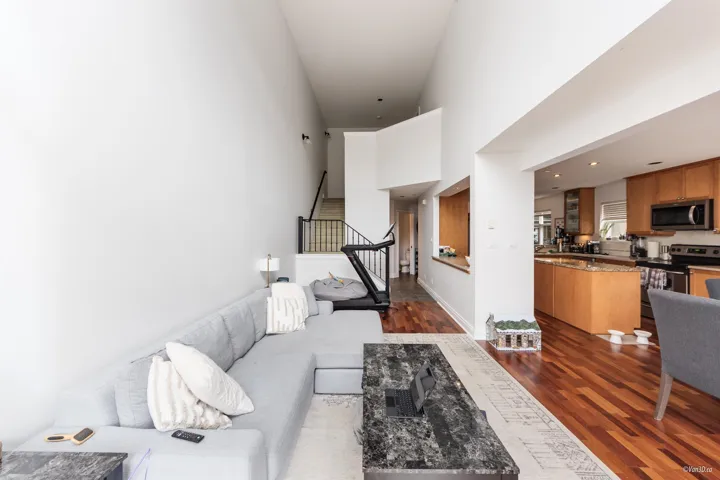 Living room featuring dark wood-type flooring, stairway, a high ceiling, and baseboards