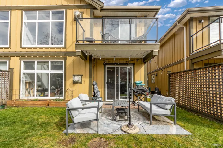 Back of property featuring a balcony, outdoor lounge area, board and batten siding, a patio area, and a yard