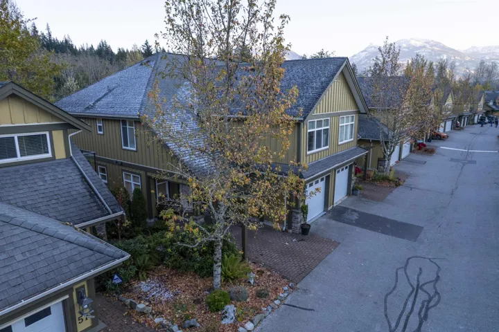 Exterior space with board and batten siding, a garage, roof with shingles, a mountain view, and driveway