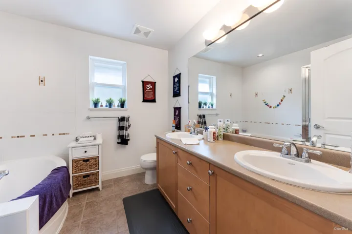 Full bathroom with a bath, double vanity, a sink, and visible vents