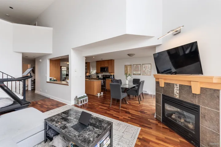Living room with a tiled fireplace, stairway, dark wood-style floors, and baseboards