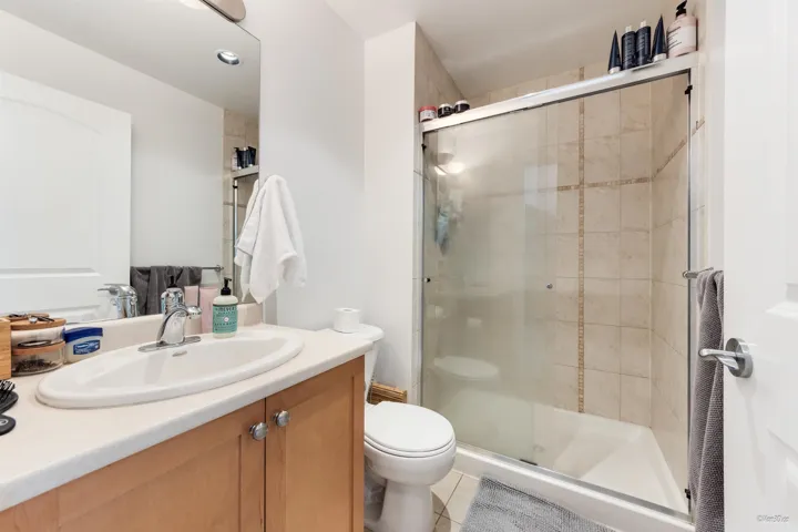 Bathroom with tile patterned floors, toilet, a shower stall, and vanity