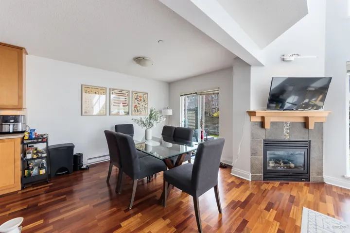 Dining room with a textured ceiling, a tile fireplace, wood finished floors, and baseboard heating