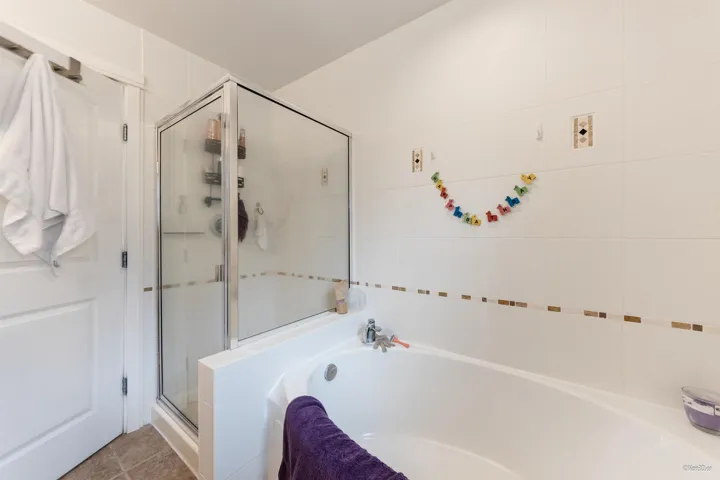 Bathroom with a stall shower, a garden tub, and tile patterned flooring