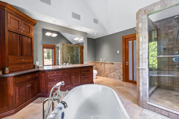 Bathroom with tile walls, vanity, a bath, a stall shower, and wainscoting