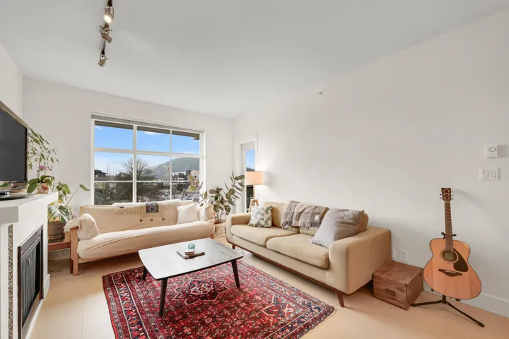 Living room with light wood-type flooring, rail lighting, and a glass covered fireplace