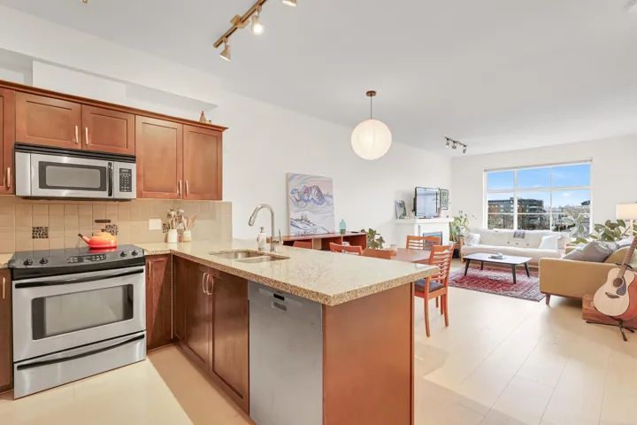 Kitchen featuring a sink, light stone countertops, a peninsula, stainless steel appliances, and decorative backsplash