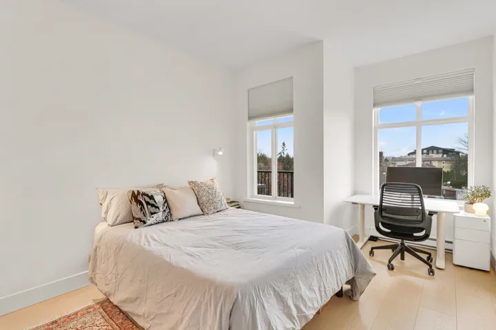 Bedroom with multiple windows, light wood-type flooring, and baseboards