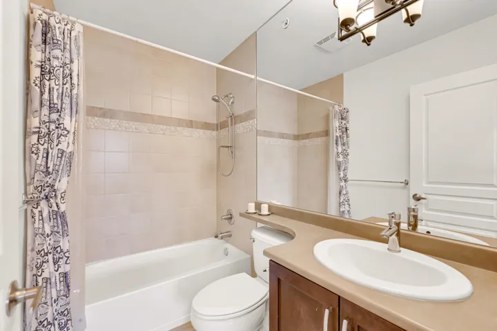 Bathroom with visible vents, toilet, vanity, and shower / bath combination with curtain