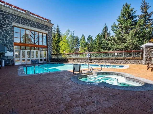 Community pool with a patio area, fence, and a hot tub