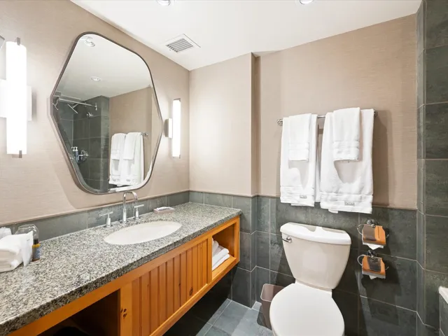 Full bathroom featuring vanity, a tile shower, tile walls, dark tile patterned floors, and wainscoting