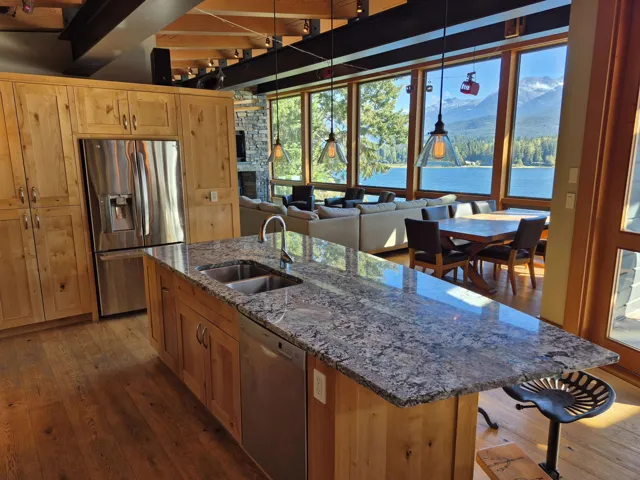 Kitchen featuring appliances with stainless steel finishes, a center island with sink, dark stone counters, a water and mountain view, and dark wood finished floors