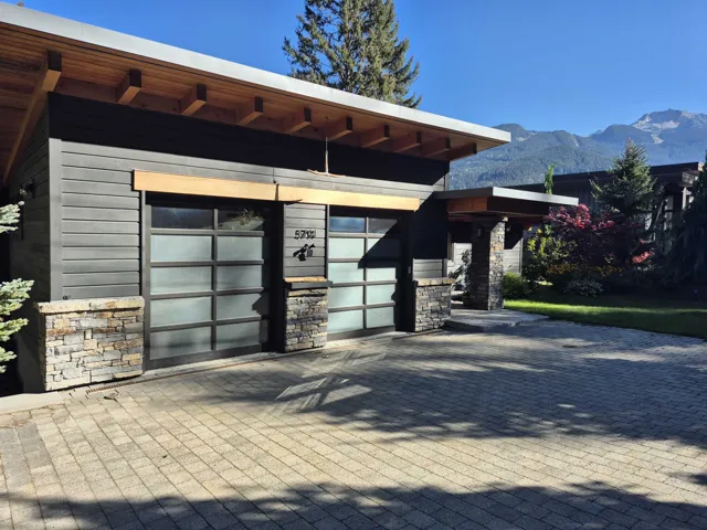 View of exterior entry with stone siding, a mountain view, and decorative driveway