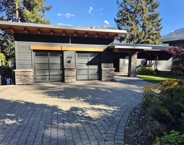 View of front facade featuring stone siding, decorative driveway, and a garage