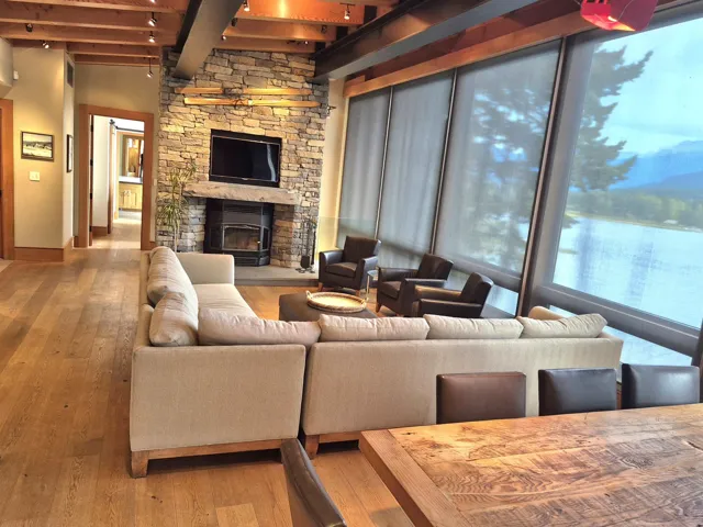 Living room featuring beam ceiling, hardwood / wood-style flooring, and a stone fireplace