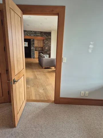 Hallway with light colored carpet and baseboards