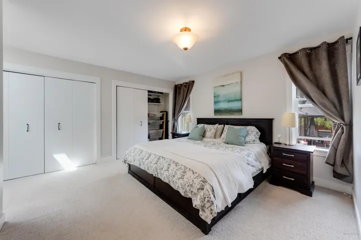 Bedroom featuring light colored carpet and two closets