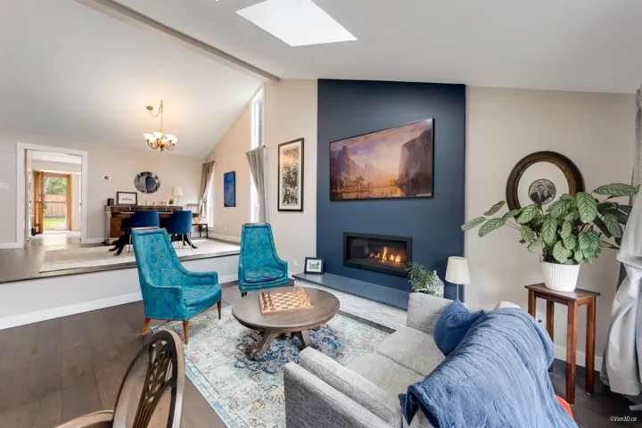 Living area featuring wood finished floors, a skylight, a glass covered fireplace, a chandelier, and baseboards