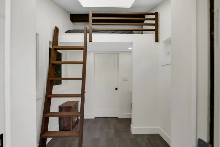 Lofted sleeping area with dark wood-finish ladder and safety railing