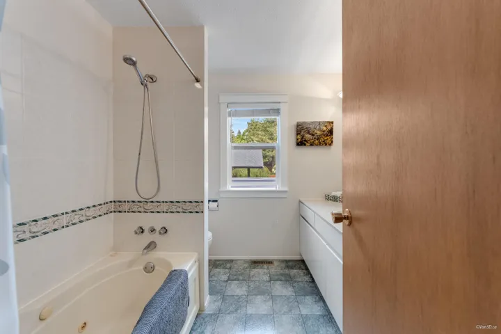 Bathroom featuring toilet, a combined bath / shower with jetted tub, vanity, and baseboards