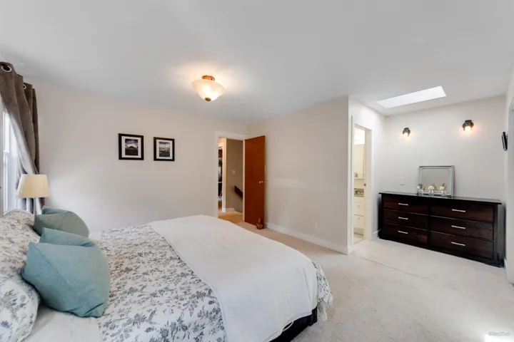 Bedroom with a skylight, light colored carpet, connected bathroom, and baseboards