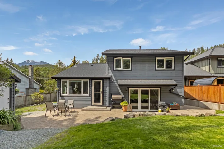Rear view of house with a patio area, a mountain view, and roof with shingles