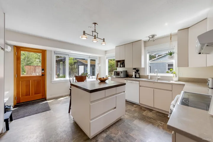 Kitchen with dishwasher, stainless steel microwave, a sink, pendant lighting, and a kitchen island