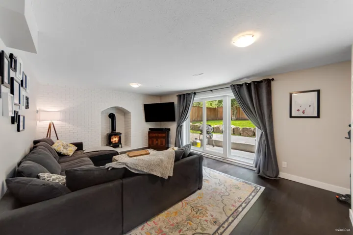 Living area with a wood stove, baseboards, dark wood-type flooring, and a textured ceiling