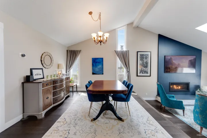 Dining space featuring a chandelier, beam ceiling, a glass covered fireplace, baseboards, and dark wood-type flooring